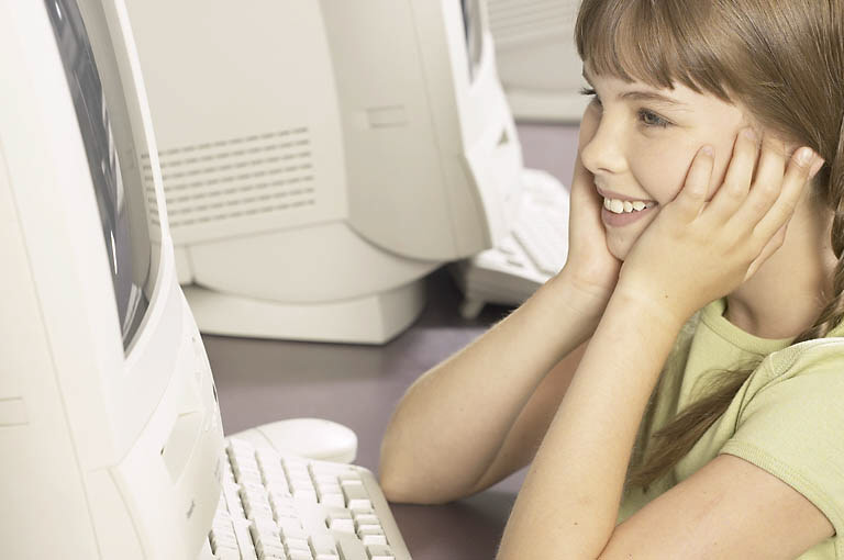 Smiling little schoolgirl using computer 1