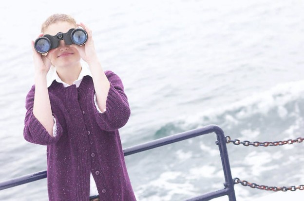 Woman looking through binoculars on boat