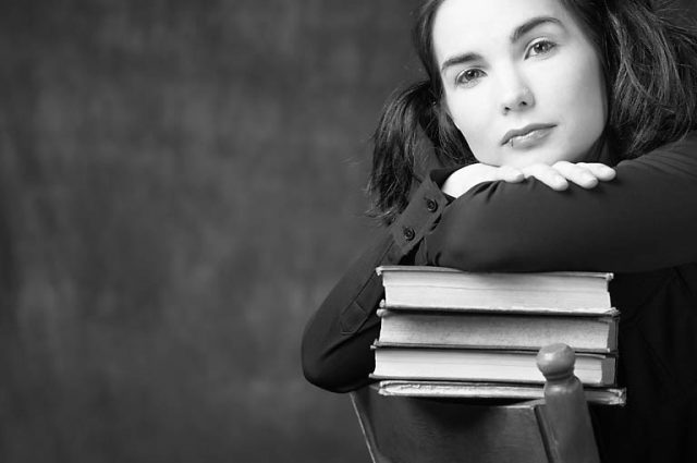 woman leaning on pile of books