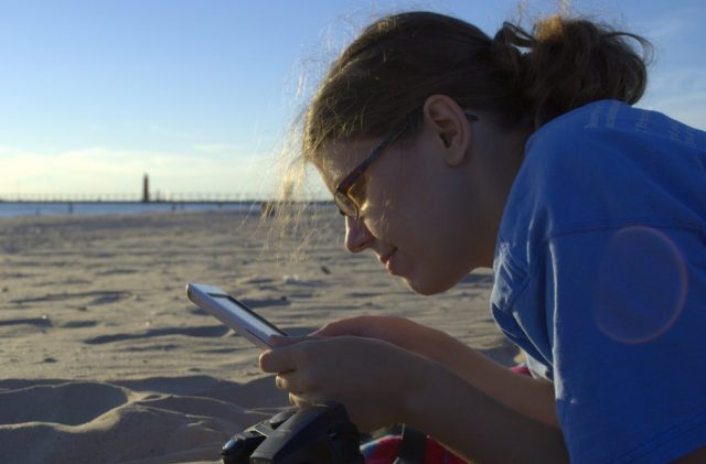 woman reading an ebook on the beach. Photo by  Michael Mol.