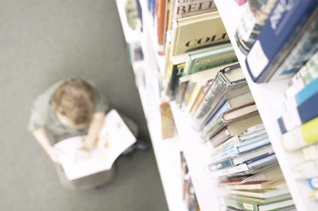 books on a library shelf, boy reading