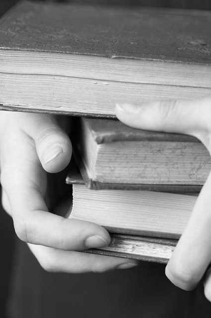 person holding stack of books in hands