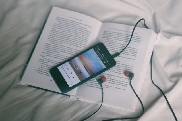 book, phone, headphones, on bed