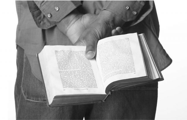 man holding an open book behind his back