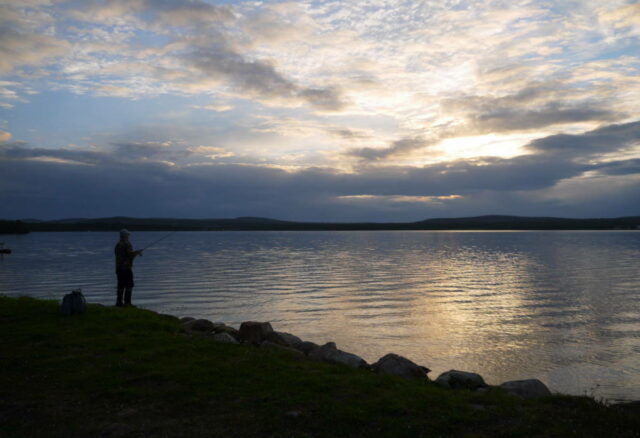 a fisherman in midnight sun at Lake Inari, Lapland