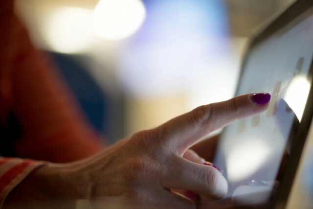 finger of old woman pointing at tablet screen. photo by timothy muza