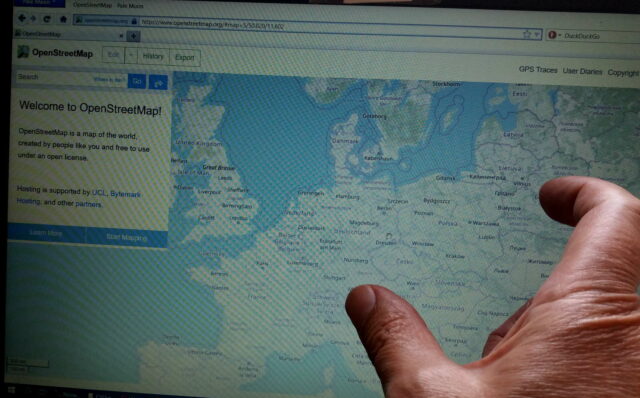 finger pointing at a map on laptop screen