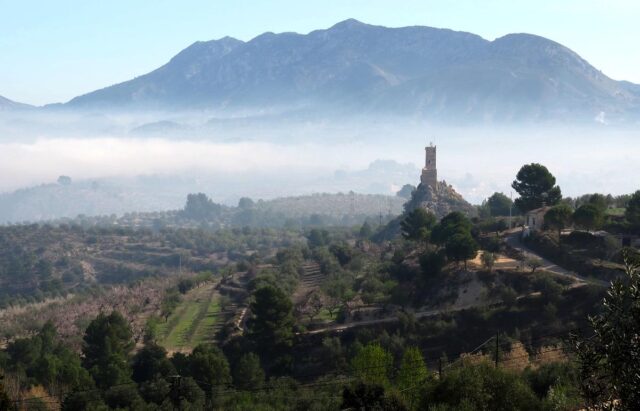 monring mist behind penella village tower in valencia province, spain