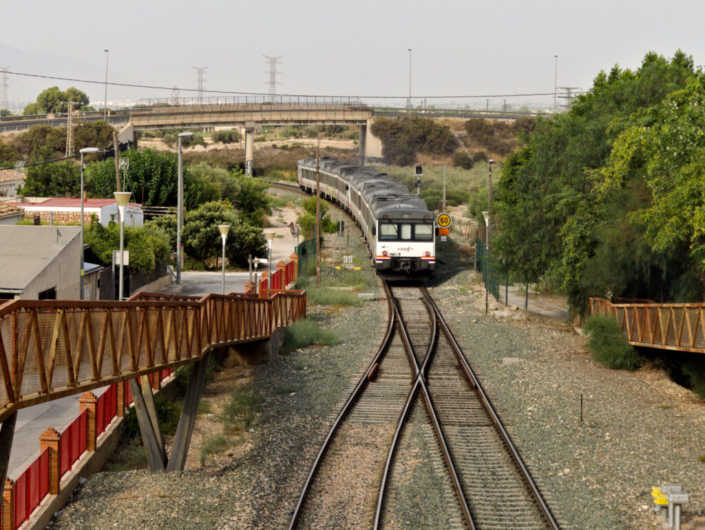 train leaving a station, tracks leading under bridge
