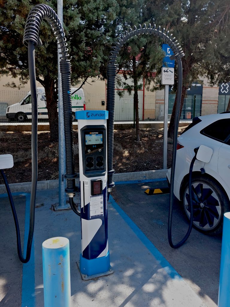electric vehicle charger in shade under trees, two ev cars charging