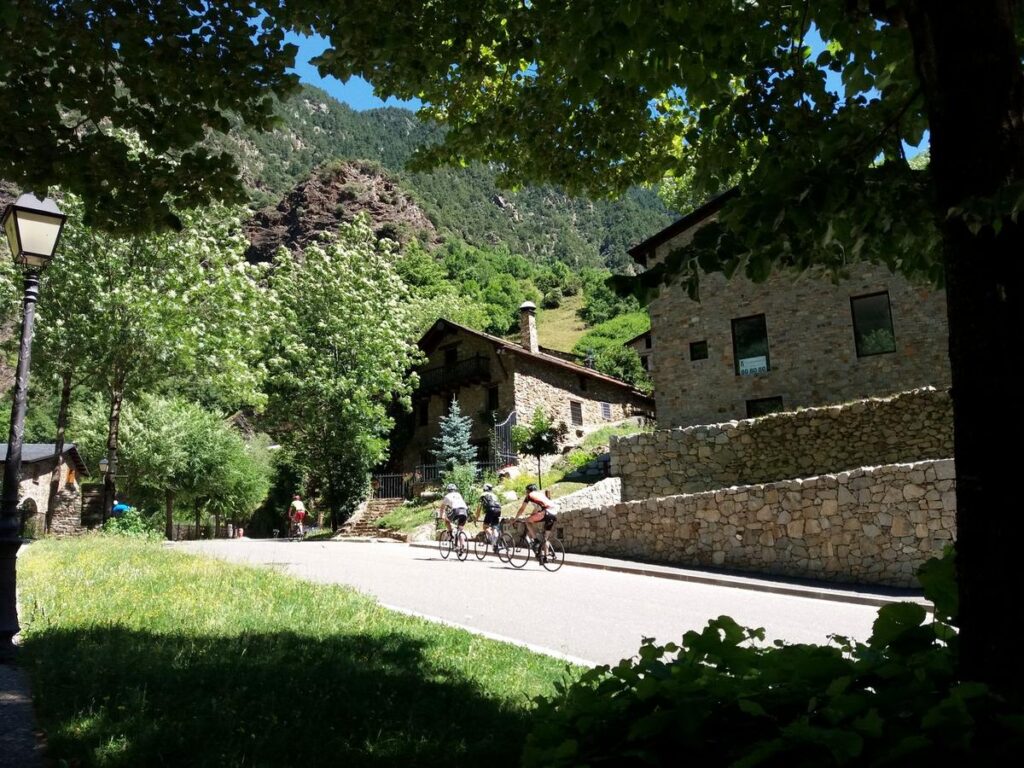 andorra - cyclists heading to a mountain across a village