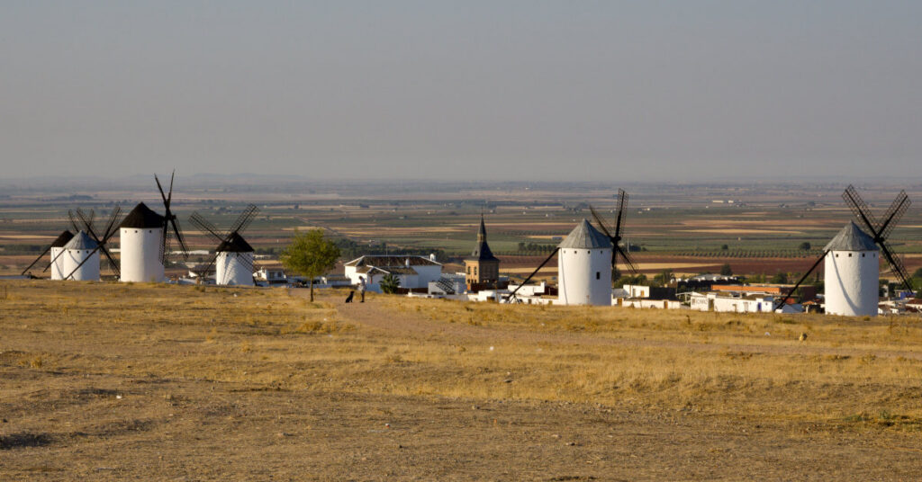 historic windmills and a dog in campo de criptana, spain