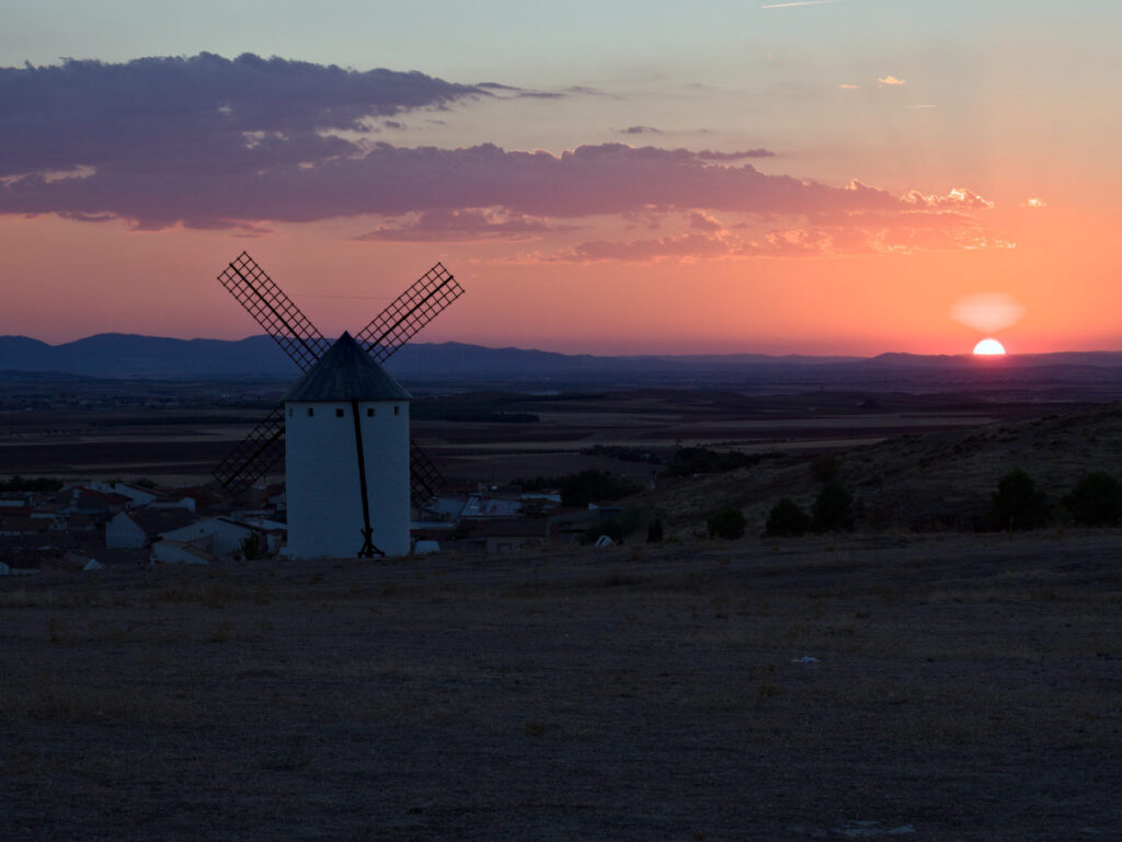 sunset in campo de criptana, spain on a hill with historic windmills